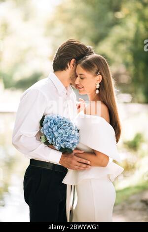 Newly-Wedded Couple Embracing Standing In Forest Outside, Vertical Stock Photo