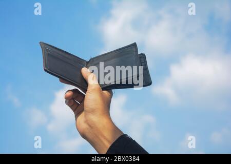 Man hands showing black wallet on sky and cloud background. Stock Photo