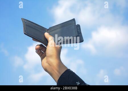 Man hands showing black wallet on sky and cloud background. Stock Photo