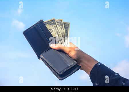 Young man hands showing dollar bills . dollar bills on sky background. Stock Photo