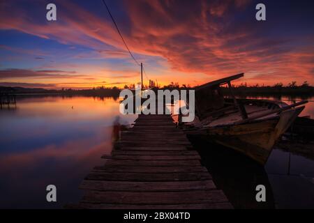 Amazing Sunset Twilight with wooden jetty and Abandon Old wreck on the shore - Landscape concept Stock Photo