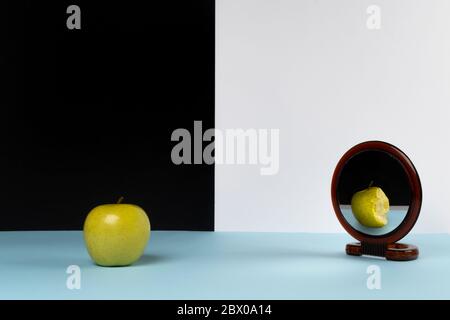 the apple in front of the mirror that appears bitten Stock Photo