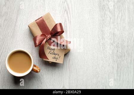 Happy Fathers Day concept. Flat lay composition with gift box, greeting card and cup of coffee on wooden table. Stock Photo