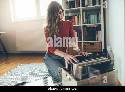 Young woman sitting on floor with vinyl record. Playing music on turntable, leisure time, hobbie Stock Photo