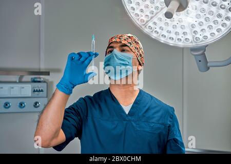 a masked surgeon against a lamp in the operating room Stock Photo