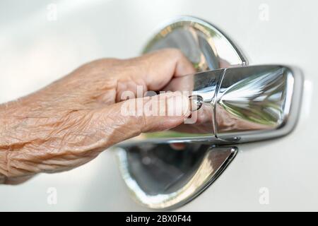 elderly woman hand opening car door Stock Photo