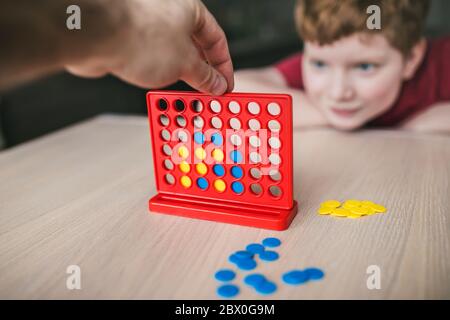 Father and son playing a board game of 'collect four in a line' - family leisure Stock Photo