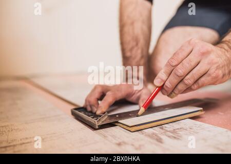 A worker makes a markup with a pencil and a square on the laminate panel for trimming Stock Photo
