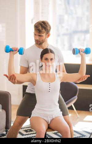 Smiling woman working on her triceps and her husband helping her Stock Photo