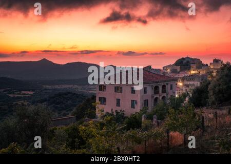 Sun setting over the ancient mountain village of Belgodere in the Balagne region  of Corsica with the Mediterranean in the distance Stock Photo