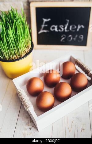 Wooden box with orange chicken eggs on a white rustic table - easter composition Stock Photo