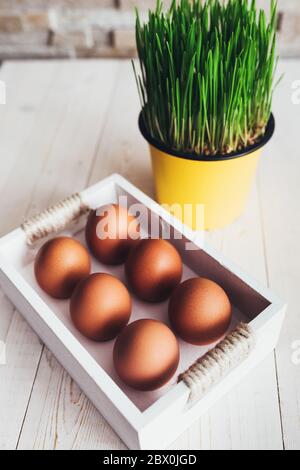 Wooden box with orange chicken eggs on a white rustic table - easter composition Stock Photo