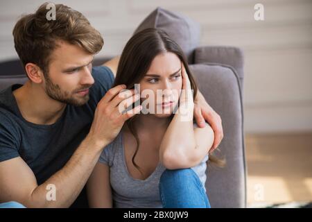 Young pretty woman looking frustrated while her husband touching her hair Stock Photo