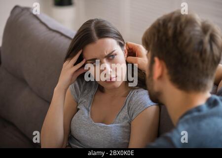 Young pretty woman looking worried while her husband talking to her Stock Photo