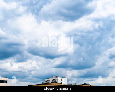 dark blue rainy clouds over roofs of urban houses on spring day Stock Photo