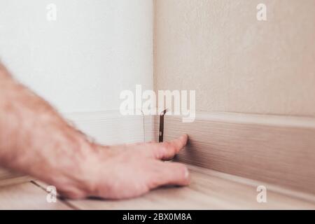 The master mounts the plastic floor plinth - finish - flooring Stock Photo