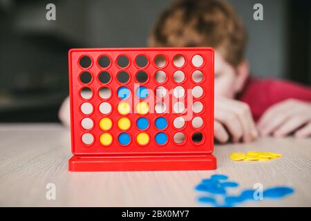 The boy wondered playing a board game four in line - home leisure Stock Photo