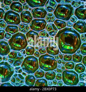 A closeup of a layer of small colourful soap bubbles floating on water Stock Photo