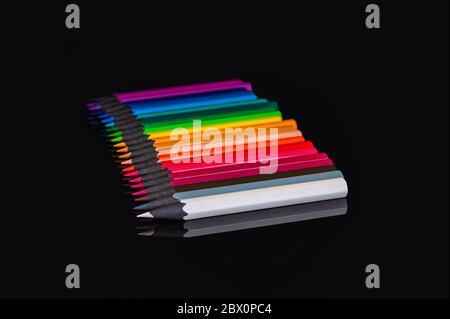 many colored pencils of different colors on an isolated black background with reflection Stock Photo