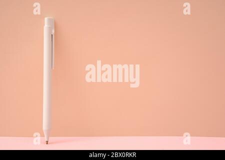 Pink color background and white ballpoint pen Stock Photo