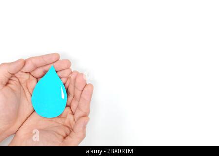 Male hands holding a blue water drop in blue background. Wash hands, csr, save water and world oceans day concept. Top view with copy space. Stock Photo