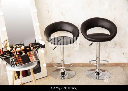Case of professional makeup artist with decorative cosmetics on table and mirror in dressing room Stock Photo
