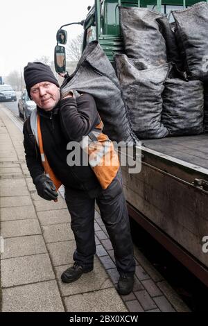 A coalman delivering sacks of house coal in a street in Longton, Stoke on Trent, Staffordshire, England Stock Photo
