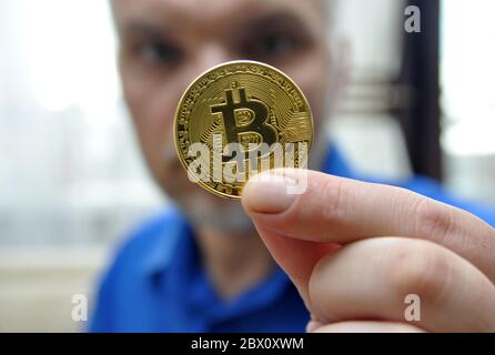 Cryptocurrency gold coin bitcoin. A man showing a cryptocurrency symbol in his hands - electronic virtual money for web banking and international Stock Photo