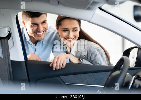 Beautiful smiling couple examining car before buying Stock Photo