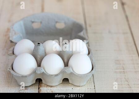 Six white shelled eggs in a cardboard egg carton. Stock Photo