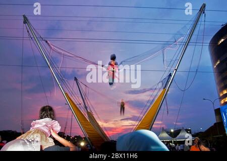 Children bouncing on a trampoline at a temporary amusement park around sunset time in Sentul, Bogor regency, West Java, Indonesia. Stock Photo