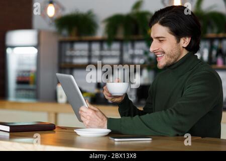 Cheerful man using digital tablet and drinking coffee Stock Photo