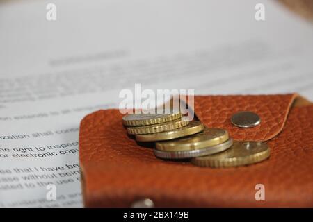 Brown leather purse or wallet and euro coins put on agreement. Work or small business contract concept Stock Photo
