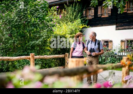 A senior pensioner couple with binoculars hiking, talking. Stock Photo