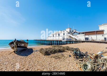 A fishing boat on the stony shingle beach by the pier on the seafront at Bognor Regis, a seaside town in West Sussex, south coast England Stock Photo