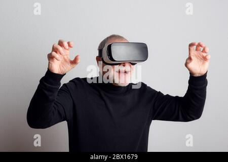 Portrait of a cheerful senior man with VR goggles in a studio. Stock Photo