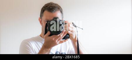 Close up isolated UK male photographer taking photograph of himself, a selfie, in interior mirror using Canon equipment. Taking professional selfie. Stock Photo