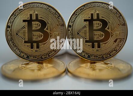 Two golden Bitcons upright standing on two other bitcoins on a white background Stock Photo