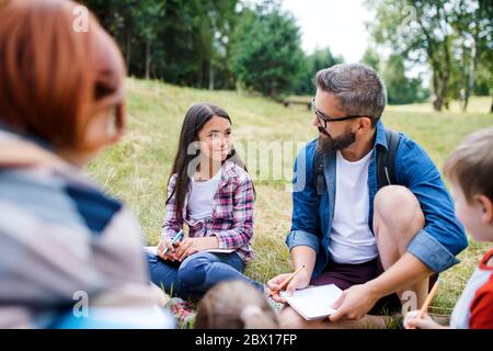 Group of school children with teacher on field trip in nature, learning science. Stock Photo