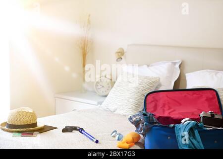 Summer holiday travel accessories prepared on the bed and mask for holiday travel in coronavirus season in bedroom. Vacation travel concept. Top view. Stock Photo