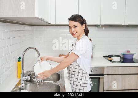 Woman hands rinsing dishes under running water in the sink Stock Photo