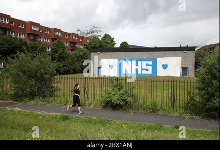 A jogger passes NHS supporting art on a wall in Glasgow as Scotland moves into phase one of the Scottish Government's plan for gradually lifting lockdown. Stock Photo