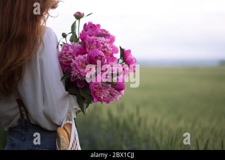 summer - Beautiful girl with a bouquet peony at the field Stock Photo