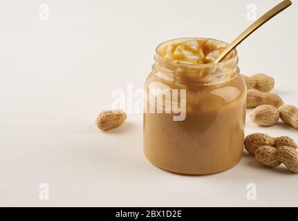 jar of peanut butter and peanuts in shell on white table, side view, Stock Photo