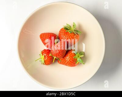Five fresh strawberries with stalks in a bowl on a white background Stock Photo