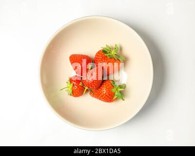 Five fresh strawberries with stalks in a bowl on a white background Stock Photo