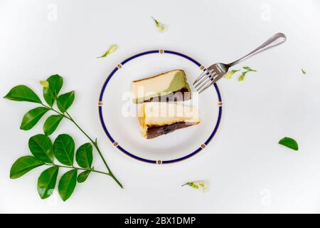 Slice of basque burnt cheesecake on plate with dessert fork on white background. Stock Photo
