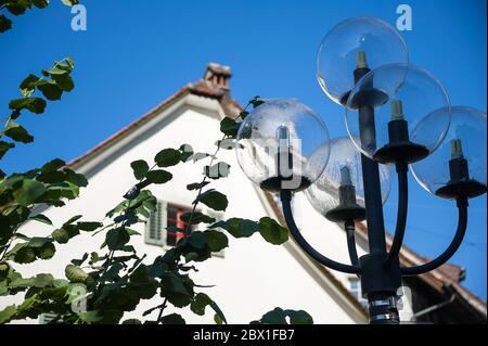 Scenic view vintage street lamp, white building exterior and clear blue sky.  Partial view to 'The Chapel of Our Lady' or Liebfrauenkappelle, in Zug Stock Photo