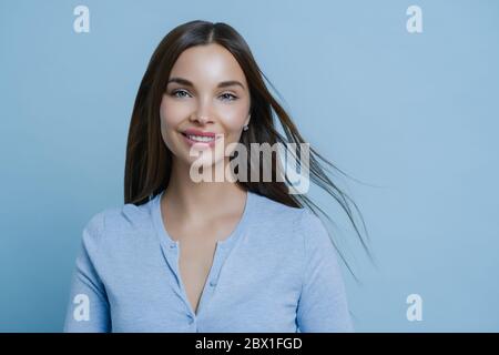 Positive lovely feminine lady happy to have first date with boyfriend, smiles broadly, has appealing appearance, glad to hear something pleasant, mode Stock Photo