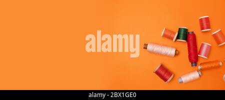 Flat lay of sewing multi-colored threads on an orange background with copyspace Stock Photo